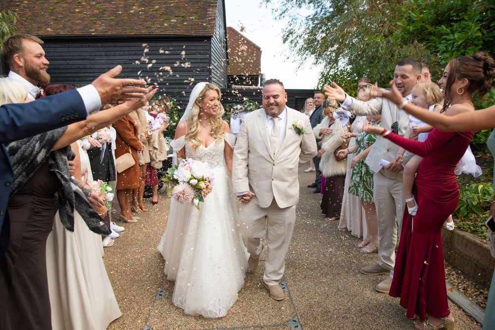 Wedding guests throw confetti as newlyweds walk through a celebratory exit line.
