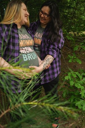 Two people share a candid moment outdoors surrounded by lush green foliage in a forest setting.