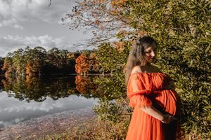 A dreamy autumn scene features a person in a billowing red gown against a misty waterside backdrop.