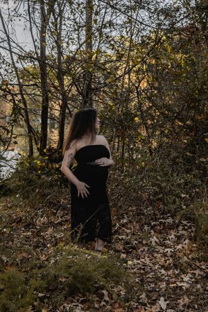 Artistic black and white photos capture graceful poses among fallen autumn leaves in a wooded setting.