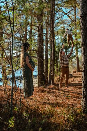 People explore a wooded trail along a scenic coastline on an autumn day with fallen leaves covering the ground.