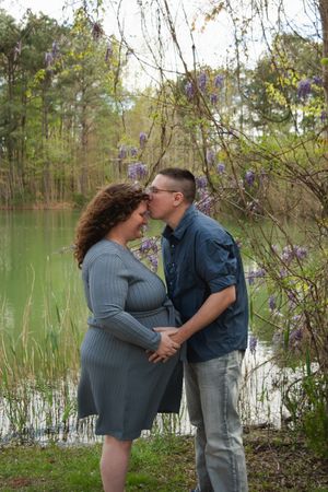 A romantic moment shared between a couple by a serene lake with spring blossoms in the background.