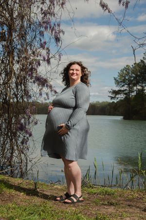 A series of four photos showing someone in a gray sweater dress posing playfully by a scenic lake on a sunny day.