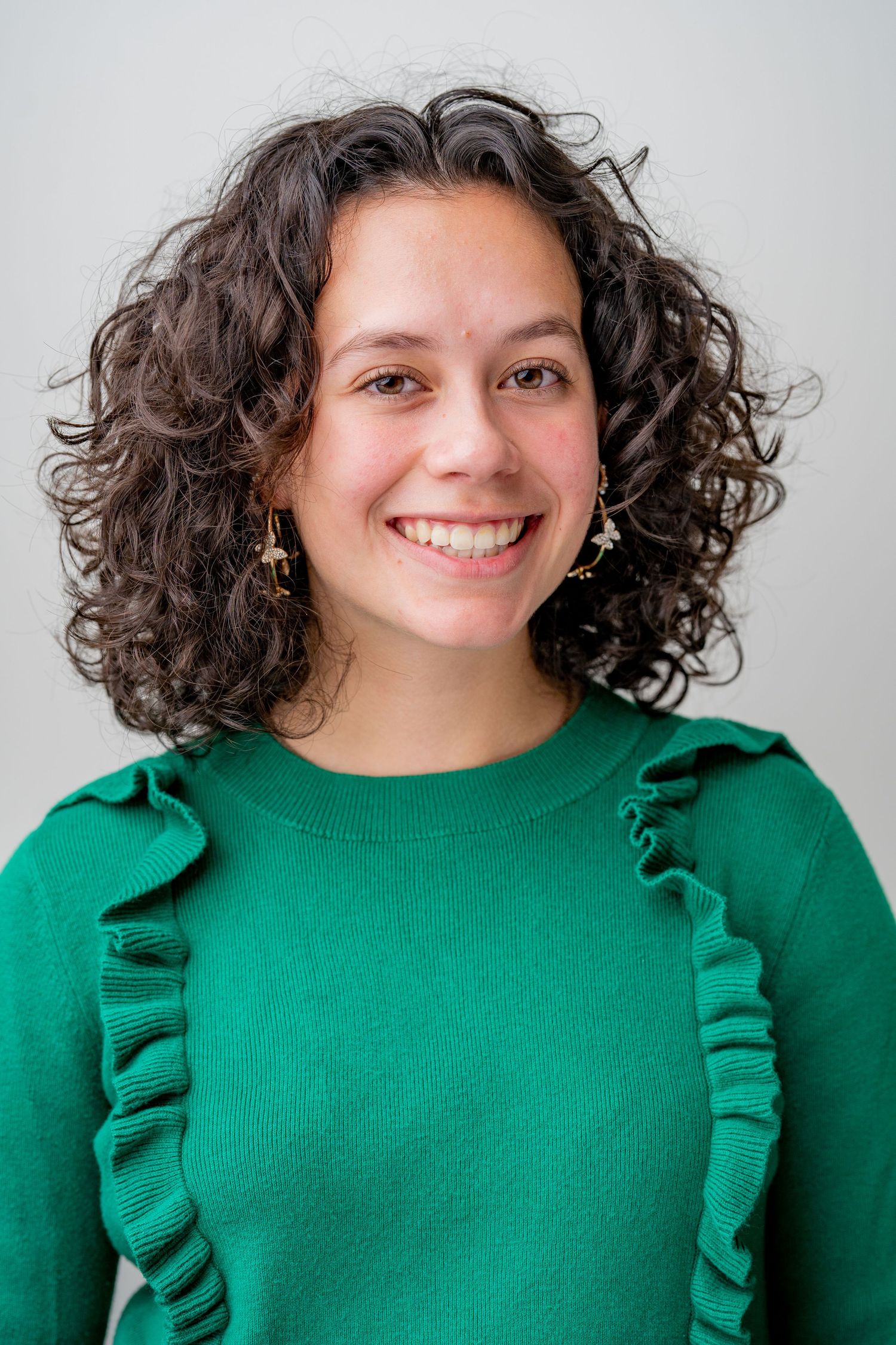 Person in emerald green ruffled sweater smiling against white background in series of four similar poses.