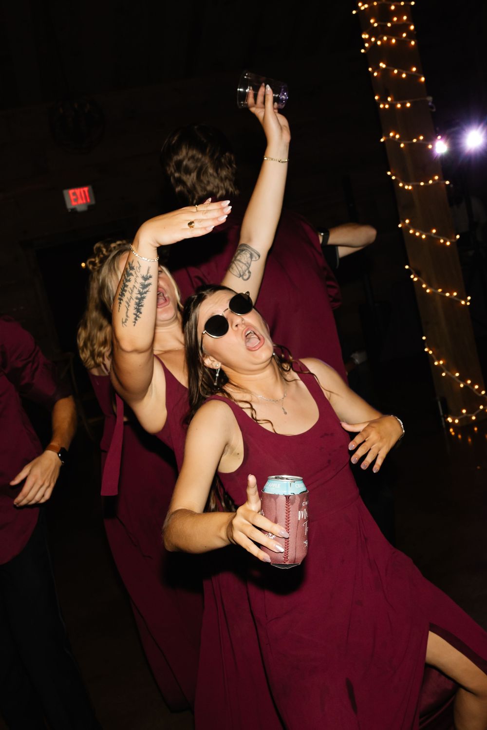 Bridesmaids in burgundy dresses dancing and having fun at wedding reception.