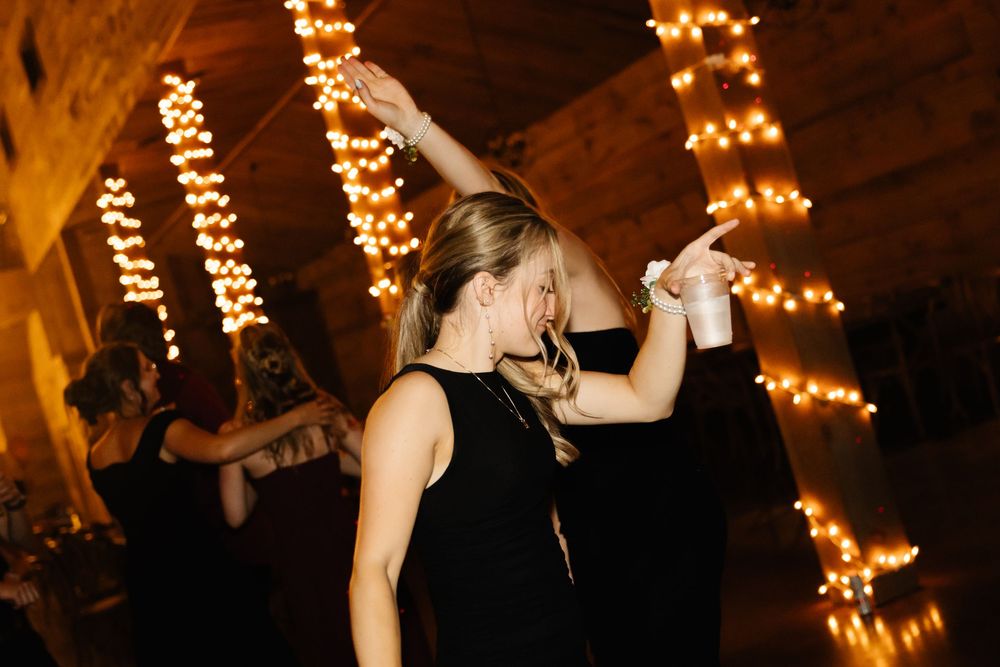 String lights create warm ambiance at rustic indoor wedding reception.