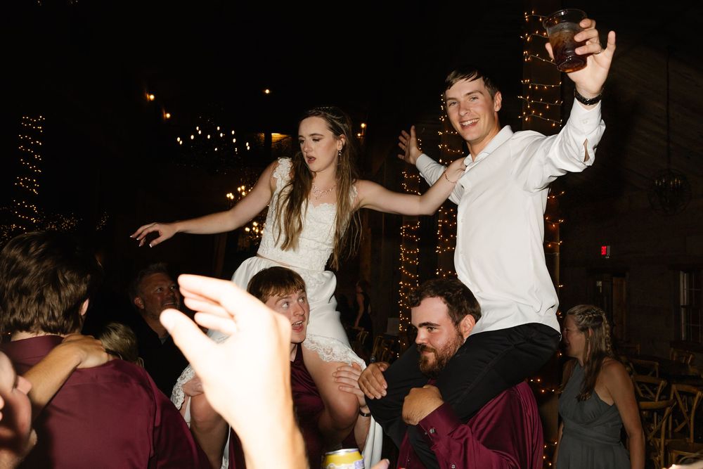 People dancing and celebrating at a lively party with twinkling lights in the background.