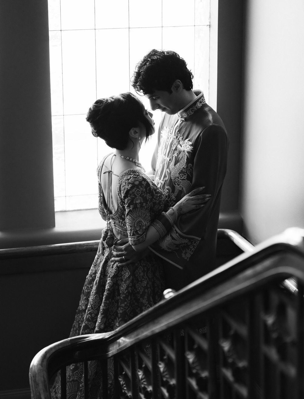 A romantic black and white photo series shows a couple in vintage dress standing together on a staircase.