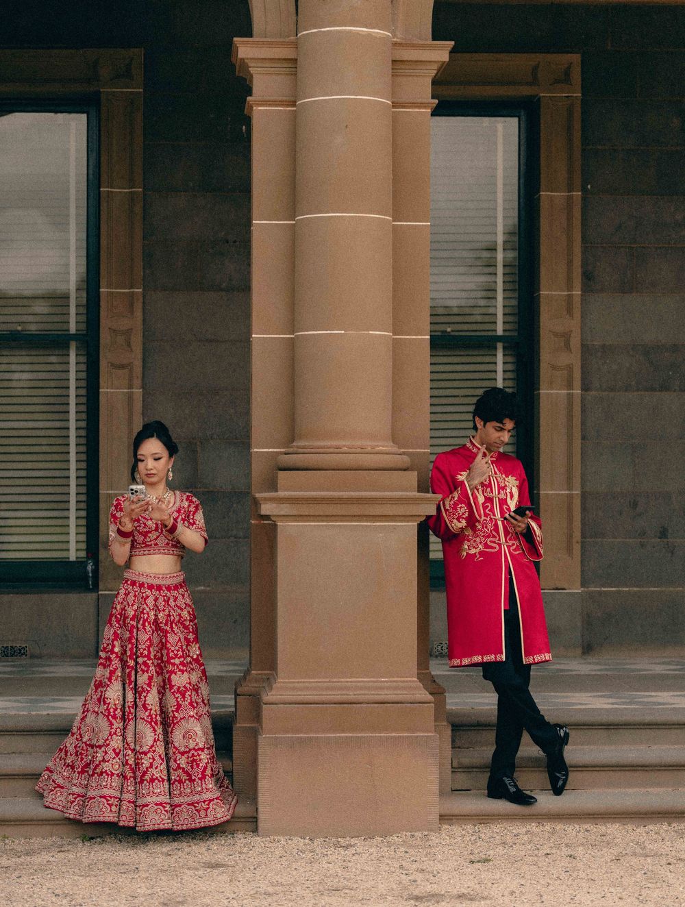A couple in traditional red Indian wedding attire poses under stone archways in a romantic photo series.