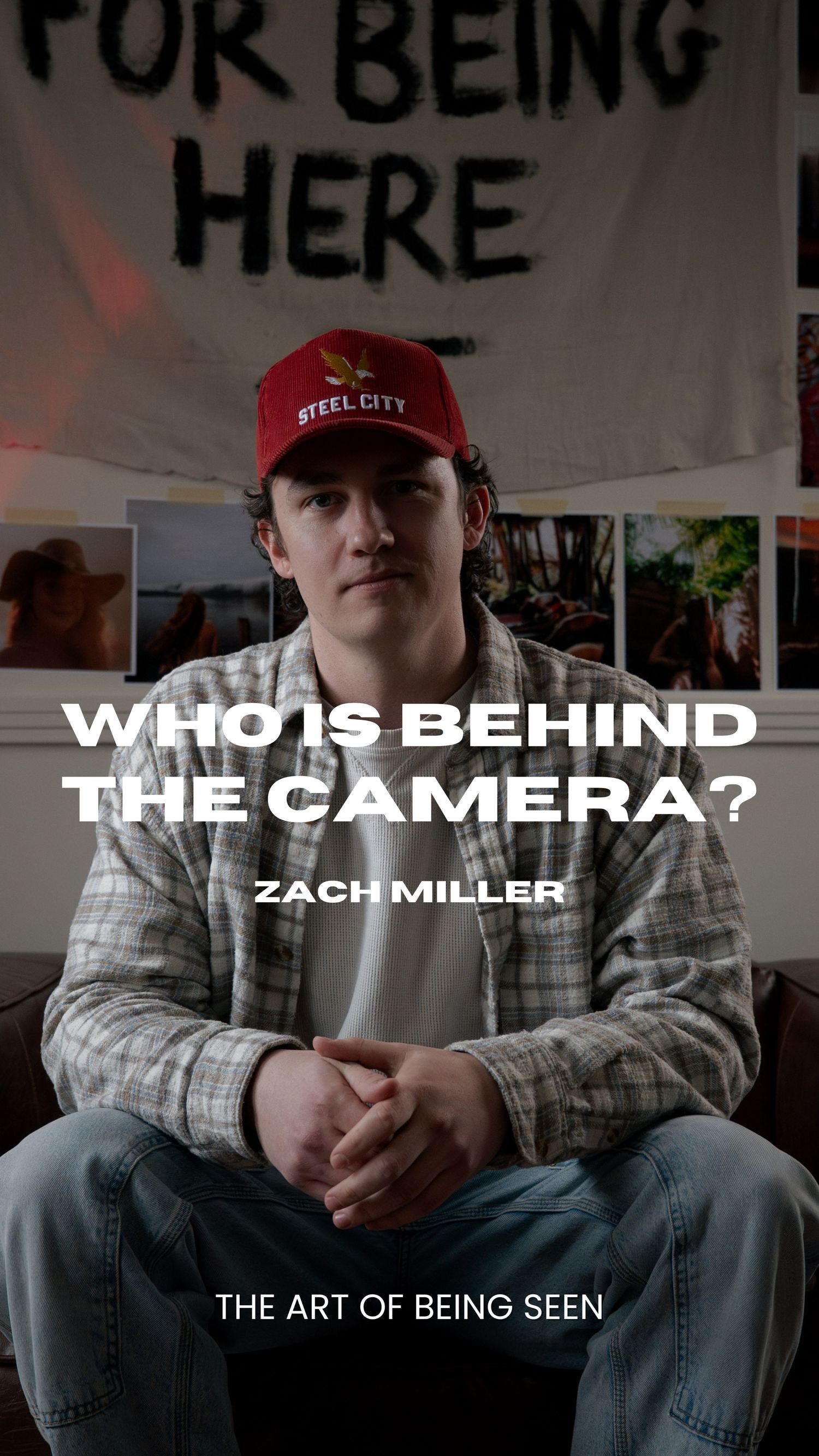 Person sitting on dark couch in casual attire with red baseball cap in room with photos on wall.