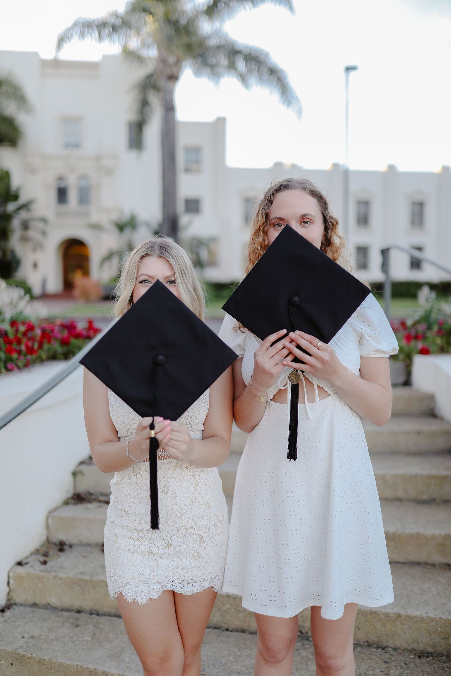 Two college graduates hold their cap to cover their faces for their grad photoshoot. Grad photos taken by Bay Area Graduation Photographer.