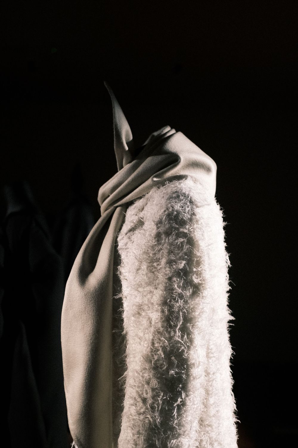 Abstract black and white photograph of a shoulder with textured white fabric against dark background.