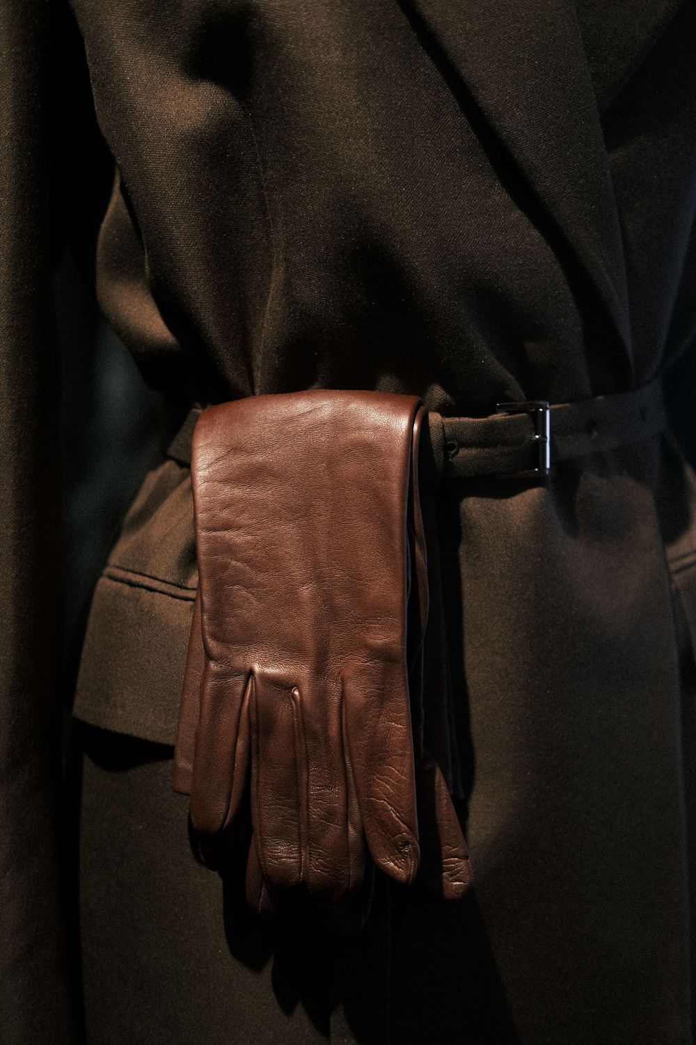 A sequence of brown leather gloves shown from different angles against a dark background.