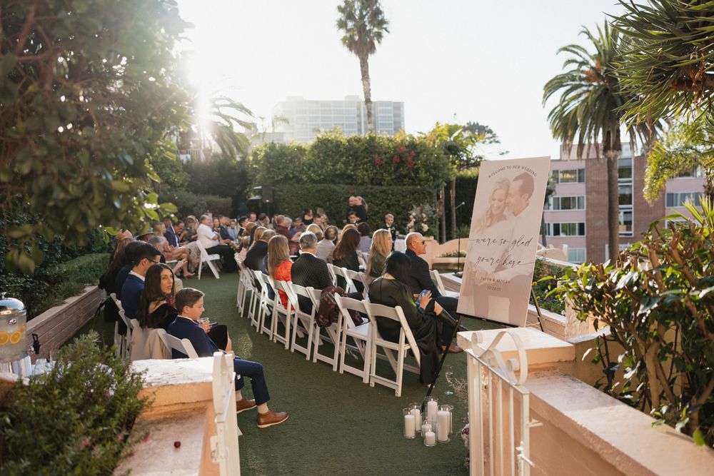 Outdoor wedding ceremony setup with white chairs and palm trees at sunset creating a romantic ambiance.