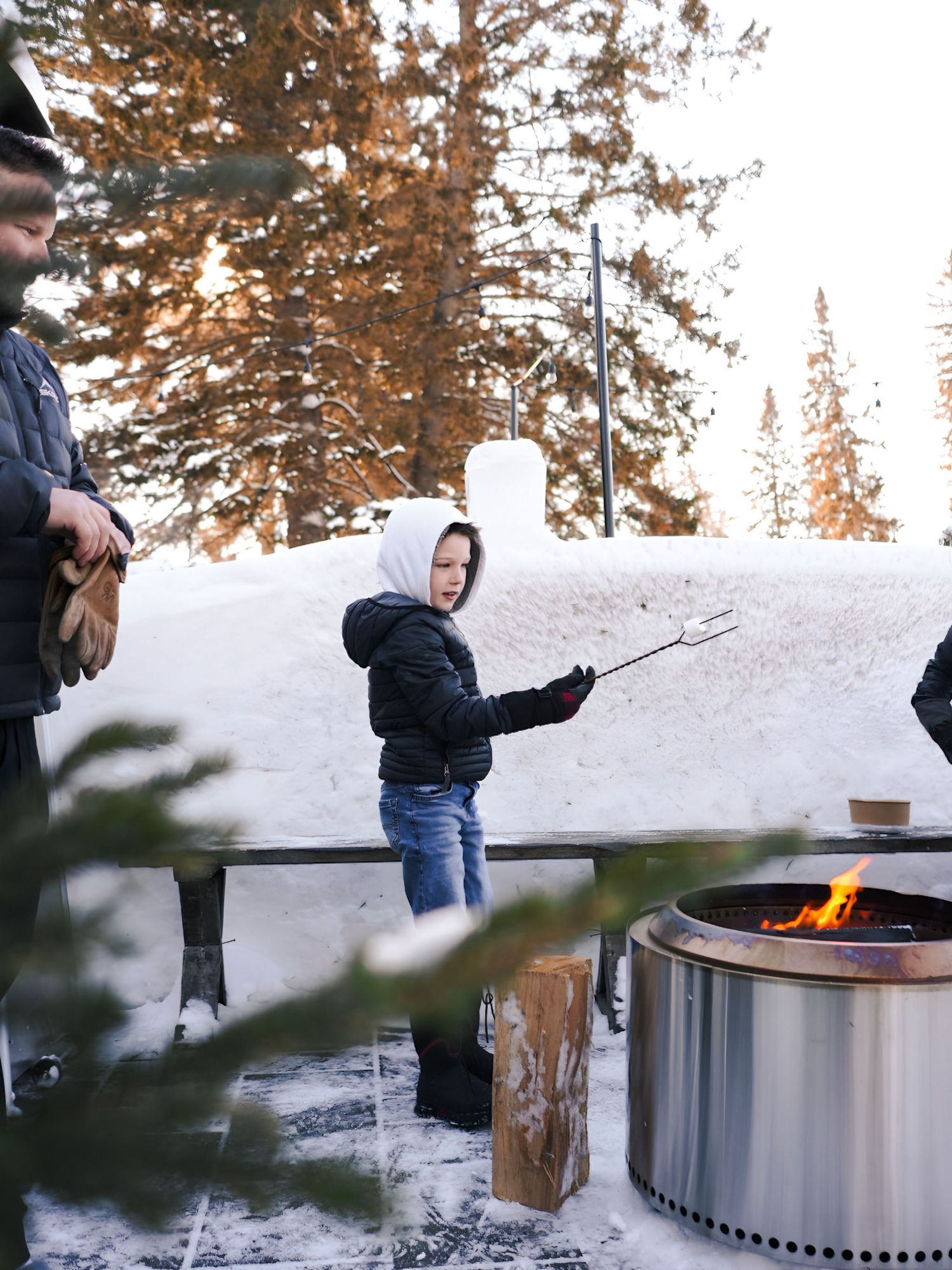 Solo stove outdoor fire pit in snowy winter setting with people gathered around enjoying the warmth.