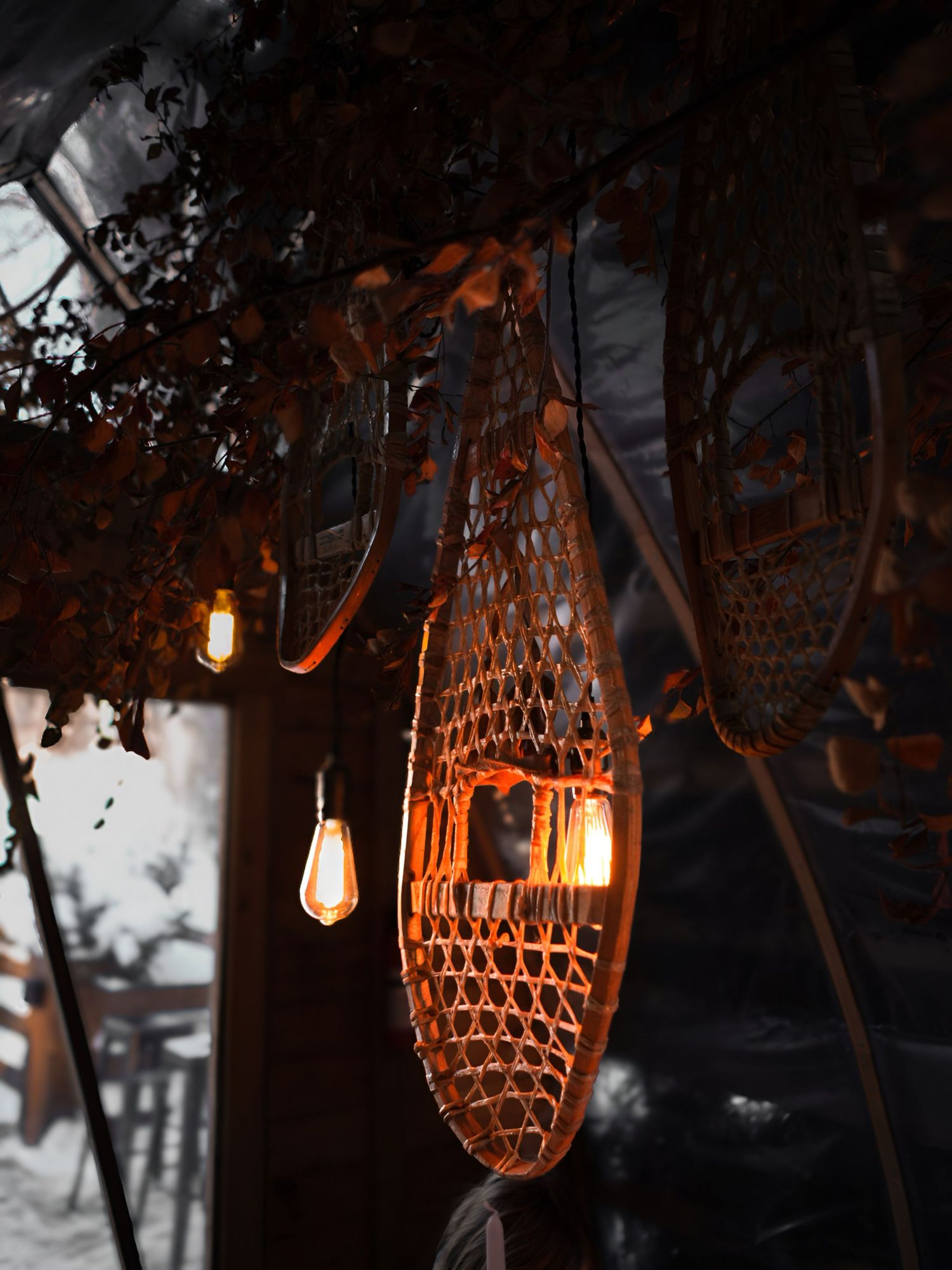 Rustic woven bamboo lanterns with warm glowing lights create an atmospheric outdoor garden setting at dusk.