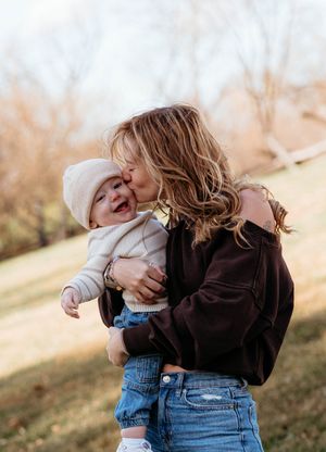 A tender moment shared outdoors on a hillside with brown jacket and denim on an autumn day.