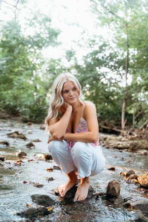 Senior portrait session by rocky creek featuring casual poses in summer attire.