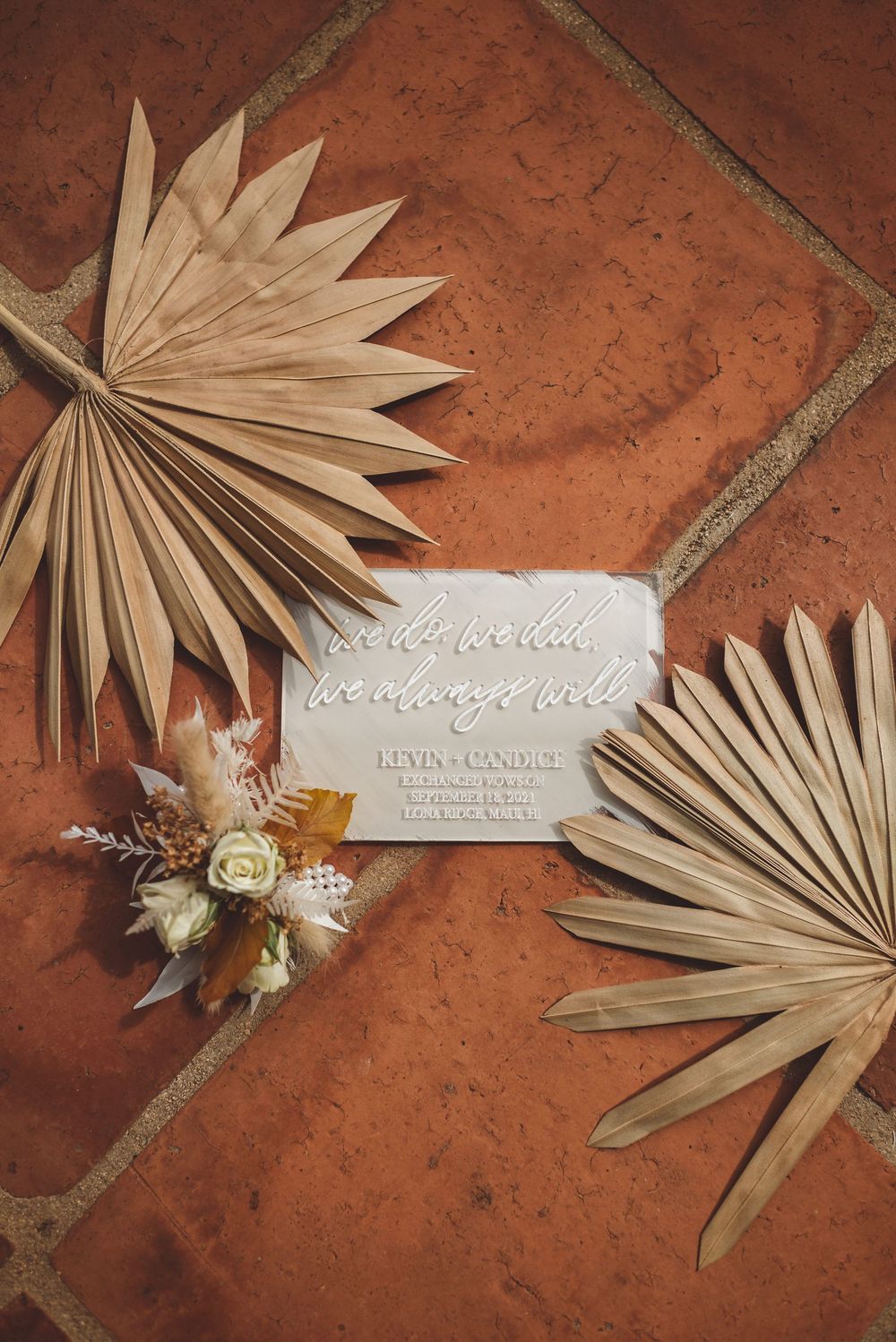 A dried palm leaf and white lace ribbon arranged artistically on terracotta tiles in a decorative composition.