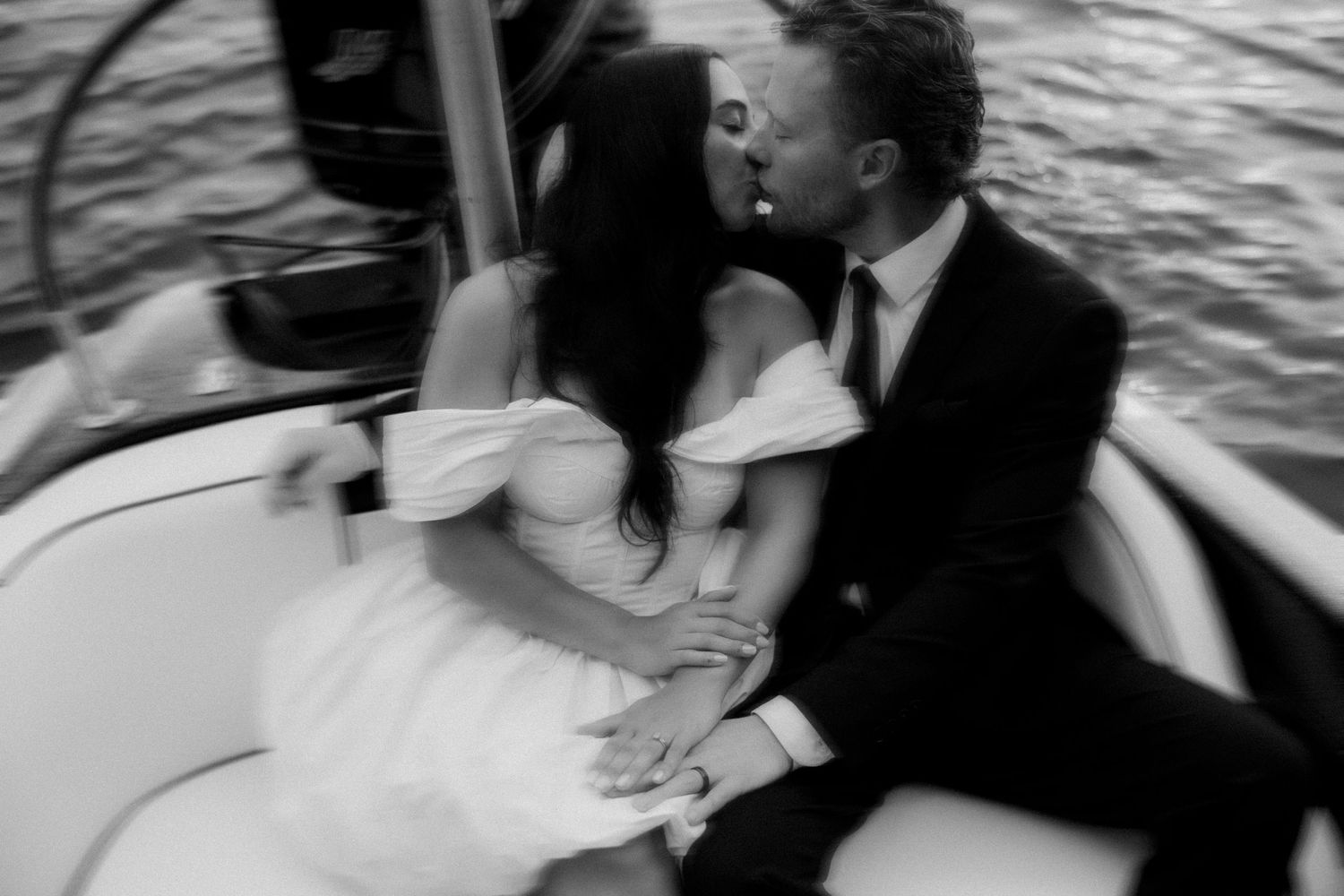 A black and white blurred motion photograph of a couple walking together at an outdoor wedding ceremony.