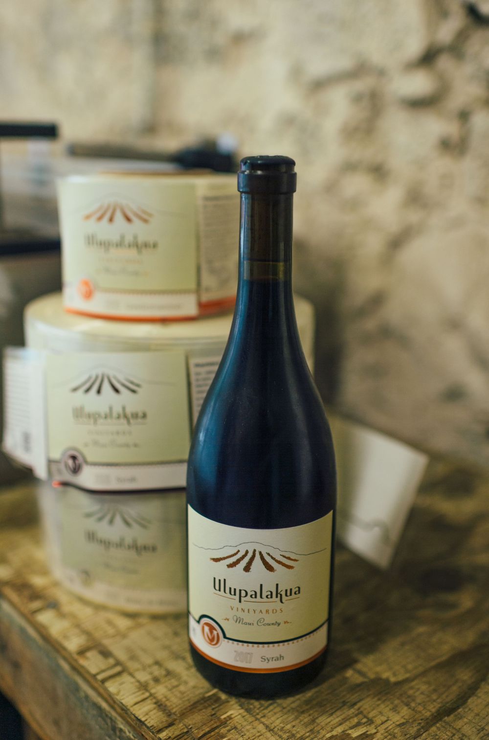 Artisanal wine bottles and labels displayed on a weathered wooden surface.