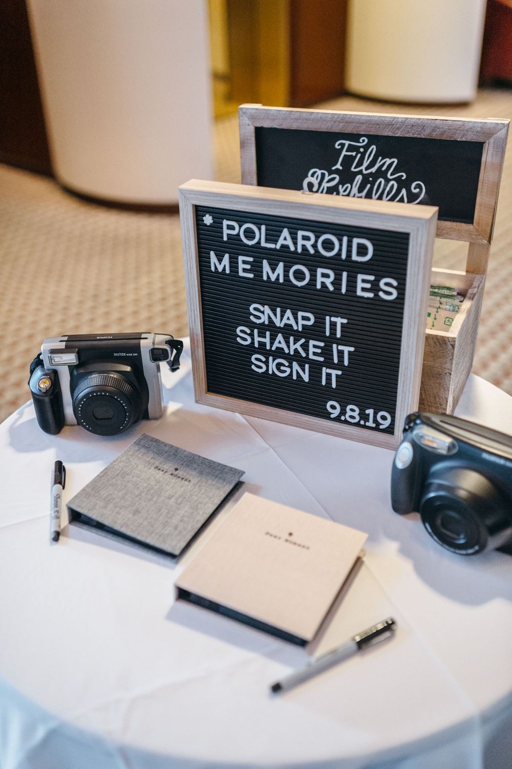 Polaroid camera guest book station with chalkboard signs for wedding memories.