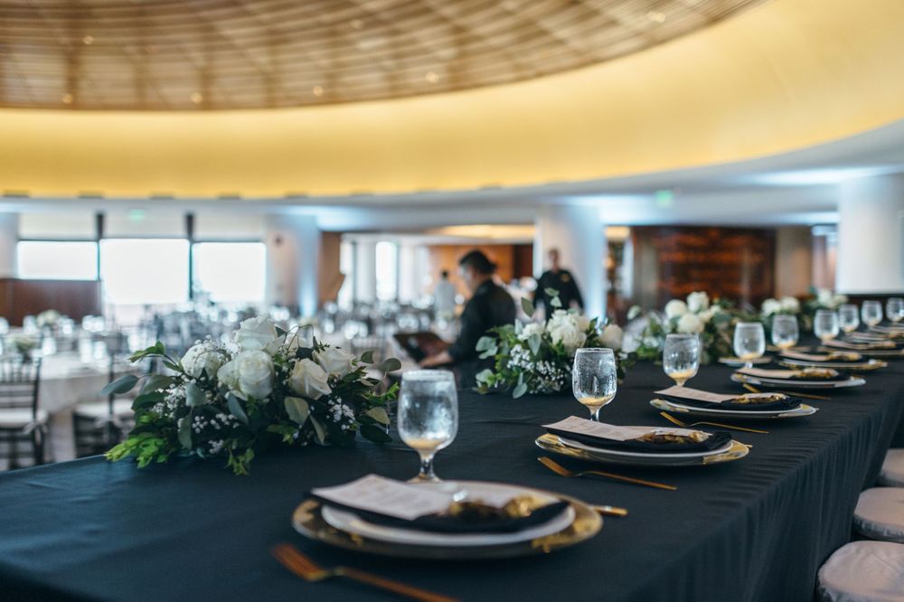 Modern wedding reception tables set with black linens and white floral centerpieces.