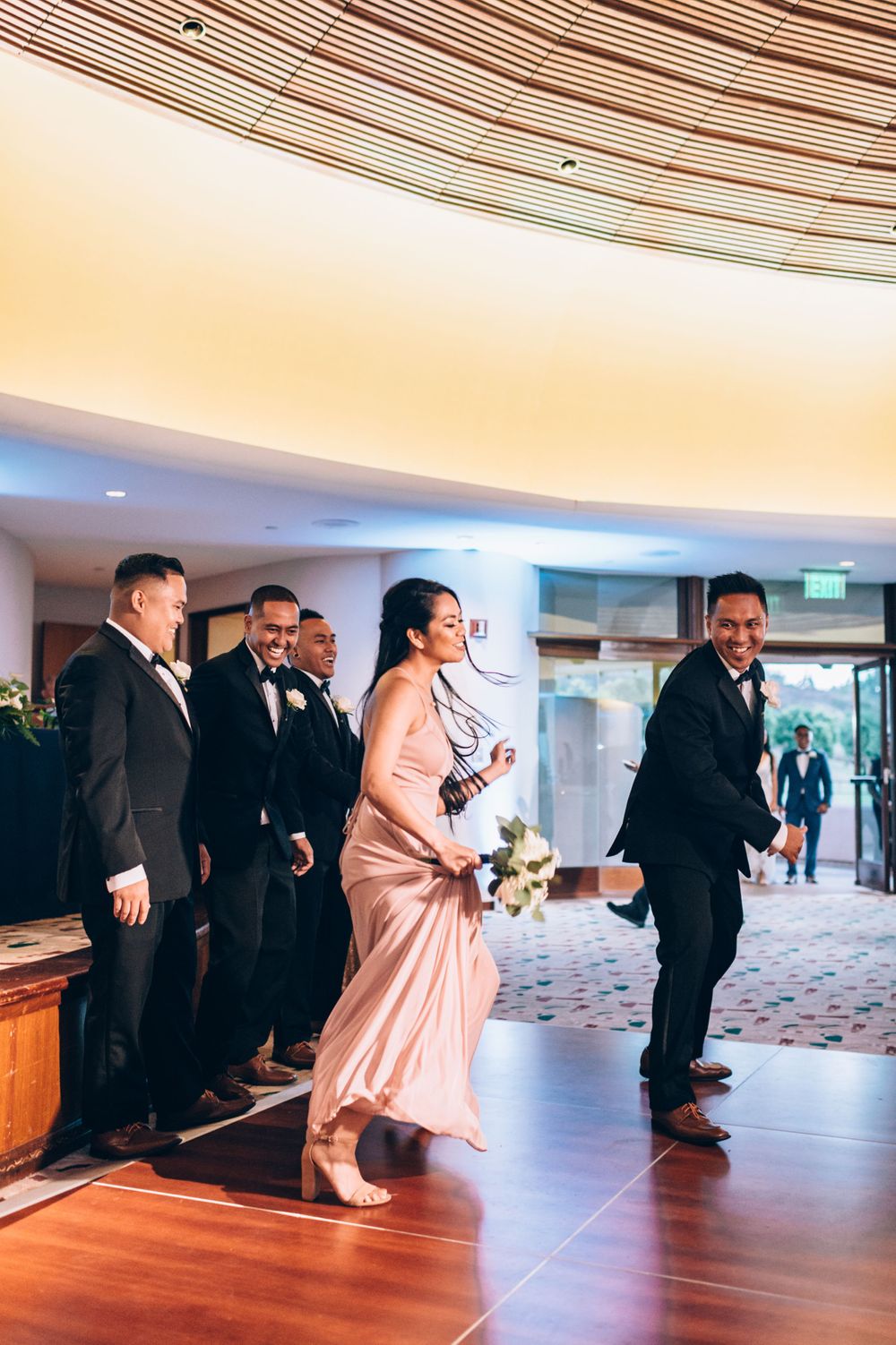 Wedding party members performing choreographed dance routine in reception hall.