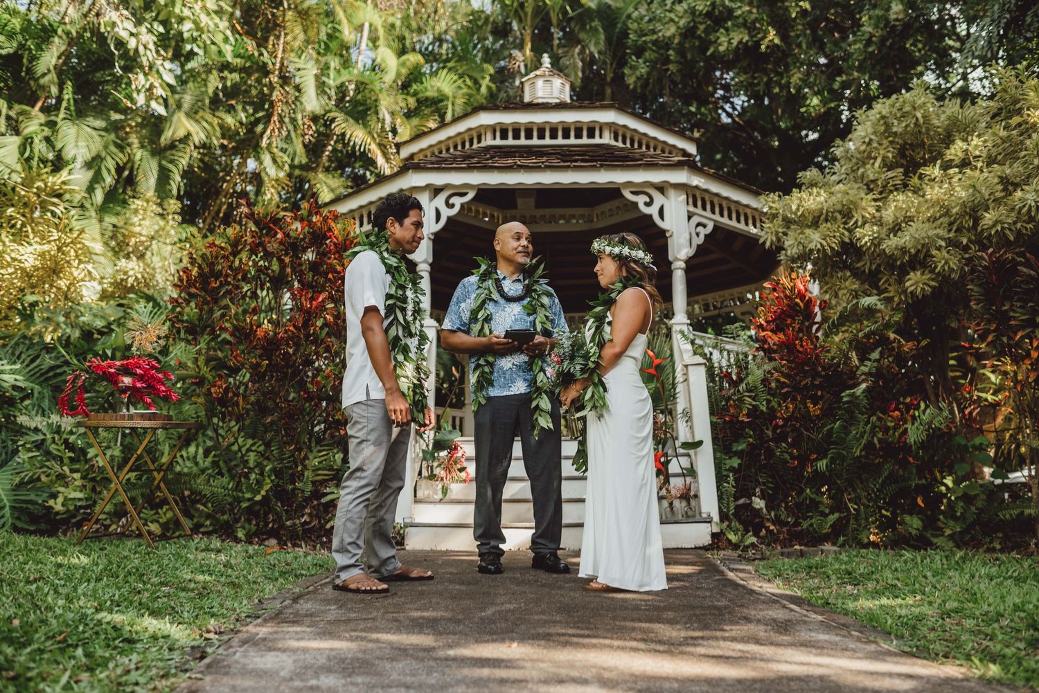 Garden wedding ceremony site with white gazebo and flowering plants along the path.