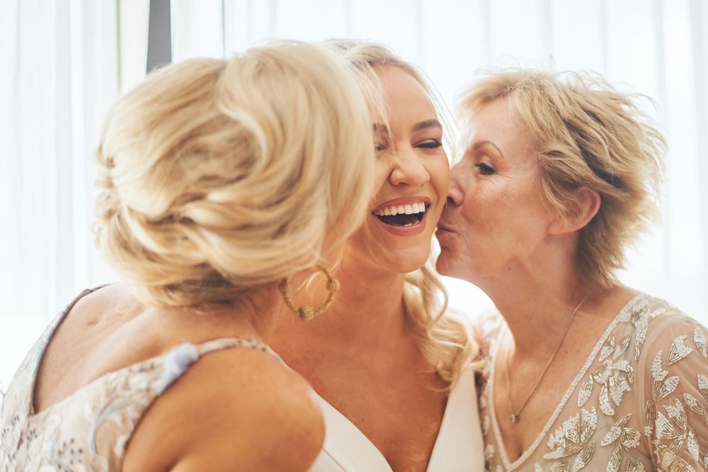 Wedding party members share joyful laughter and embraces while getting ready.
