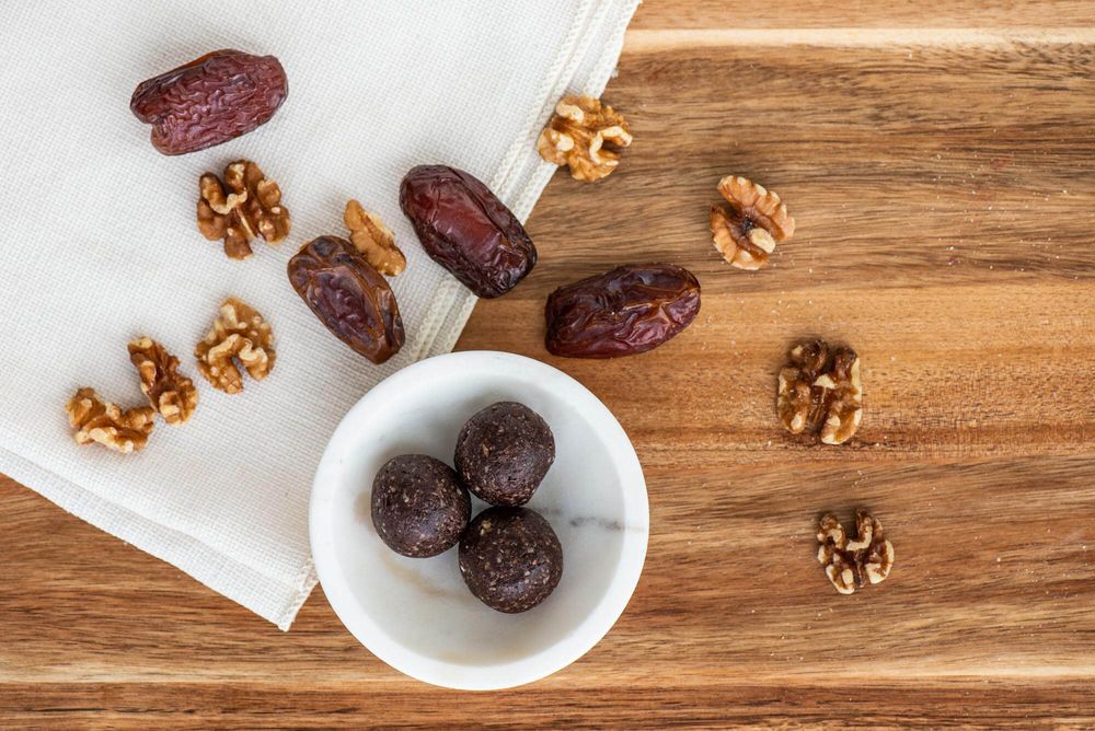 Fresh dates and walnuts scattered on a rustic wooden surface.