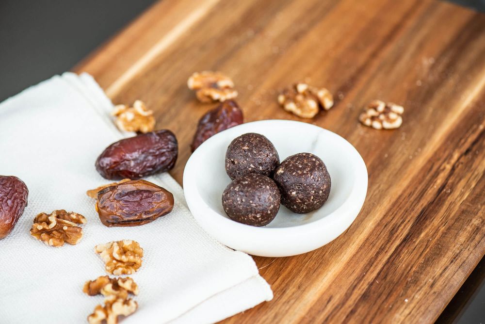 Medjool dates and walnuts arranged on a wooden cutting board.