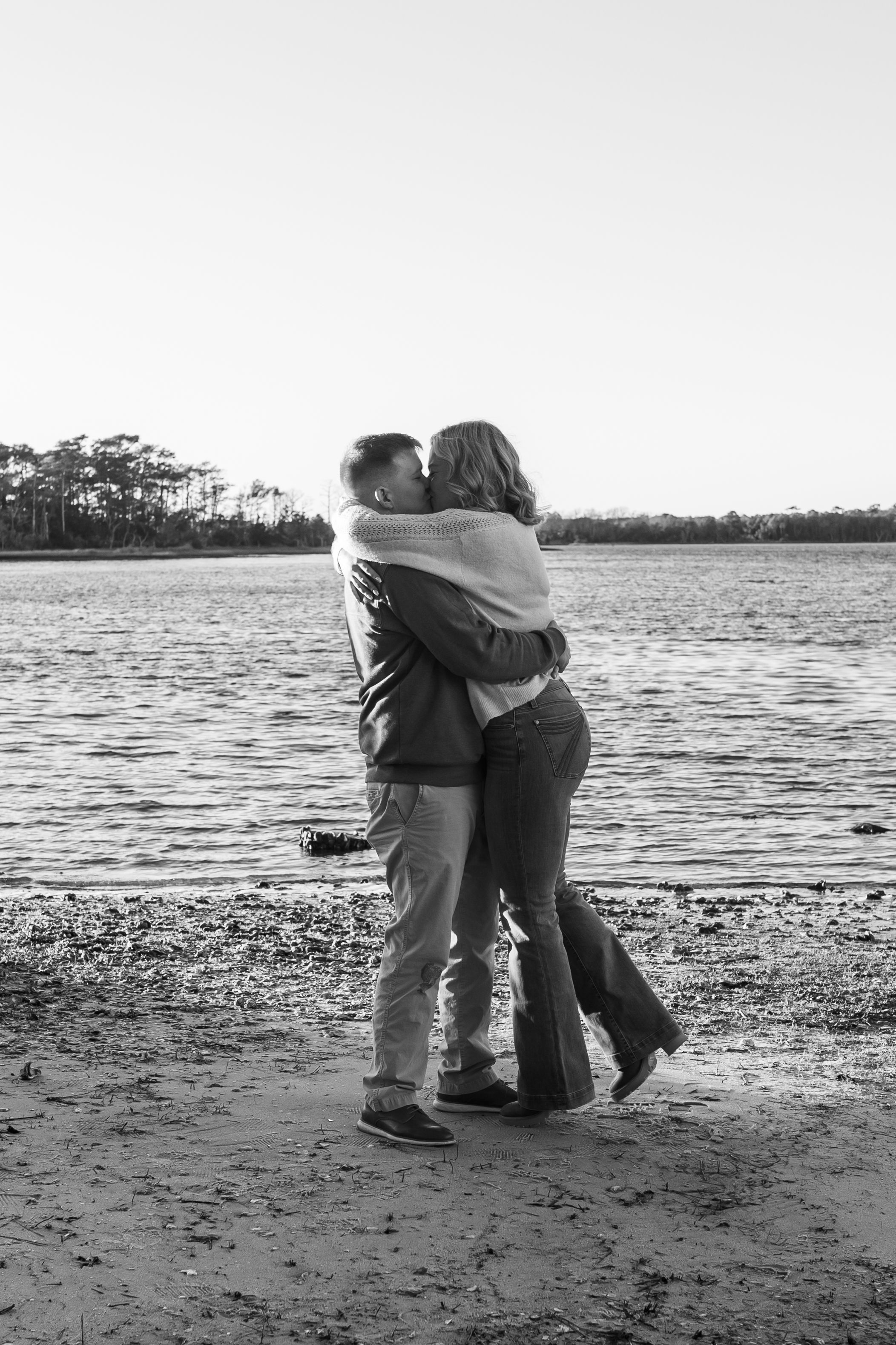 Newly engaged couple strolling along the Crystal Coast shoreline at sunset engagement session
