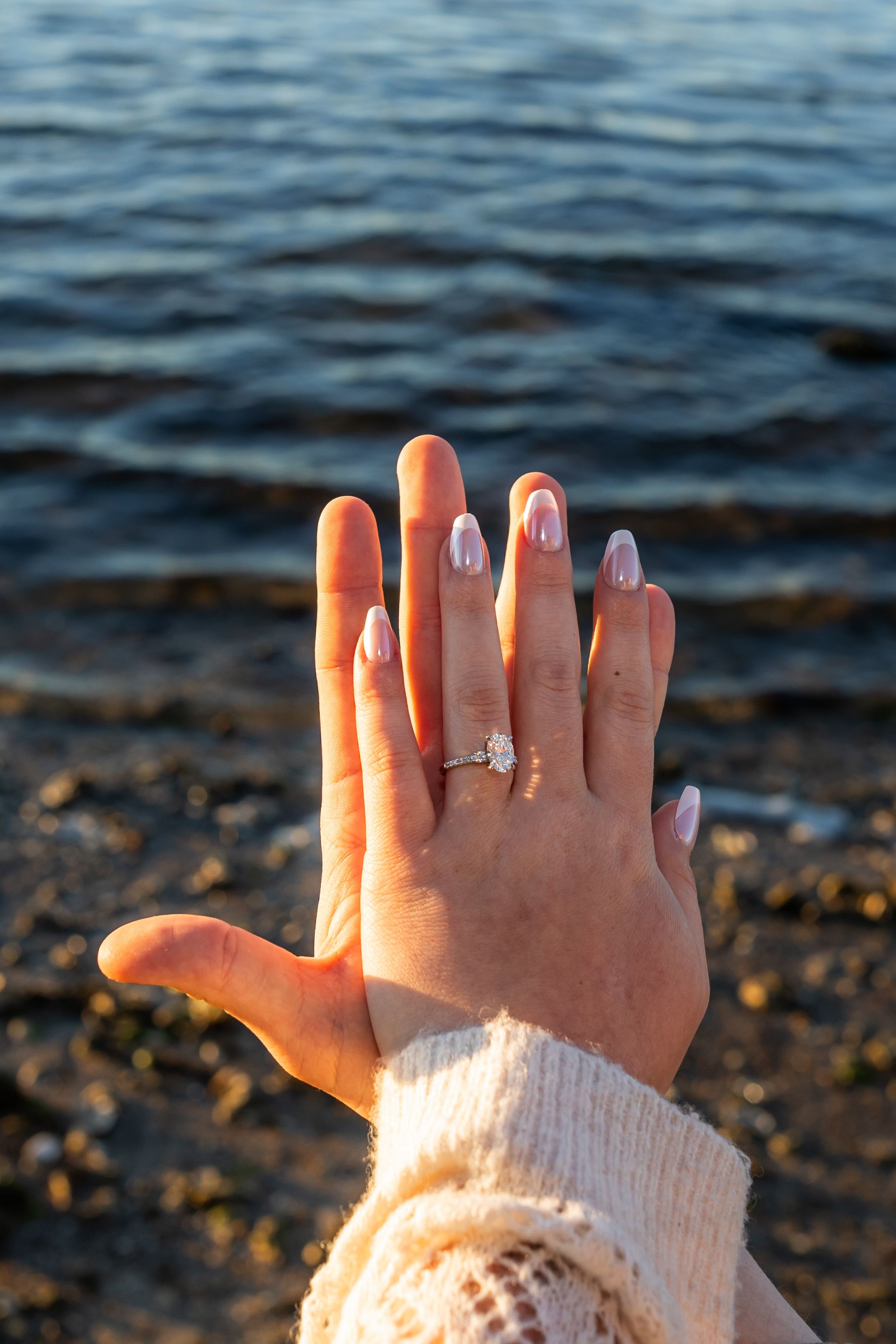 Engagement ring held over ocean backdrop on Emerald Isle during coastal proposal photography