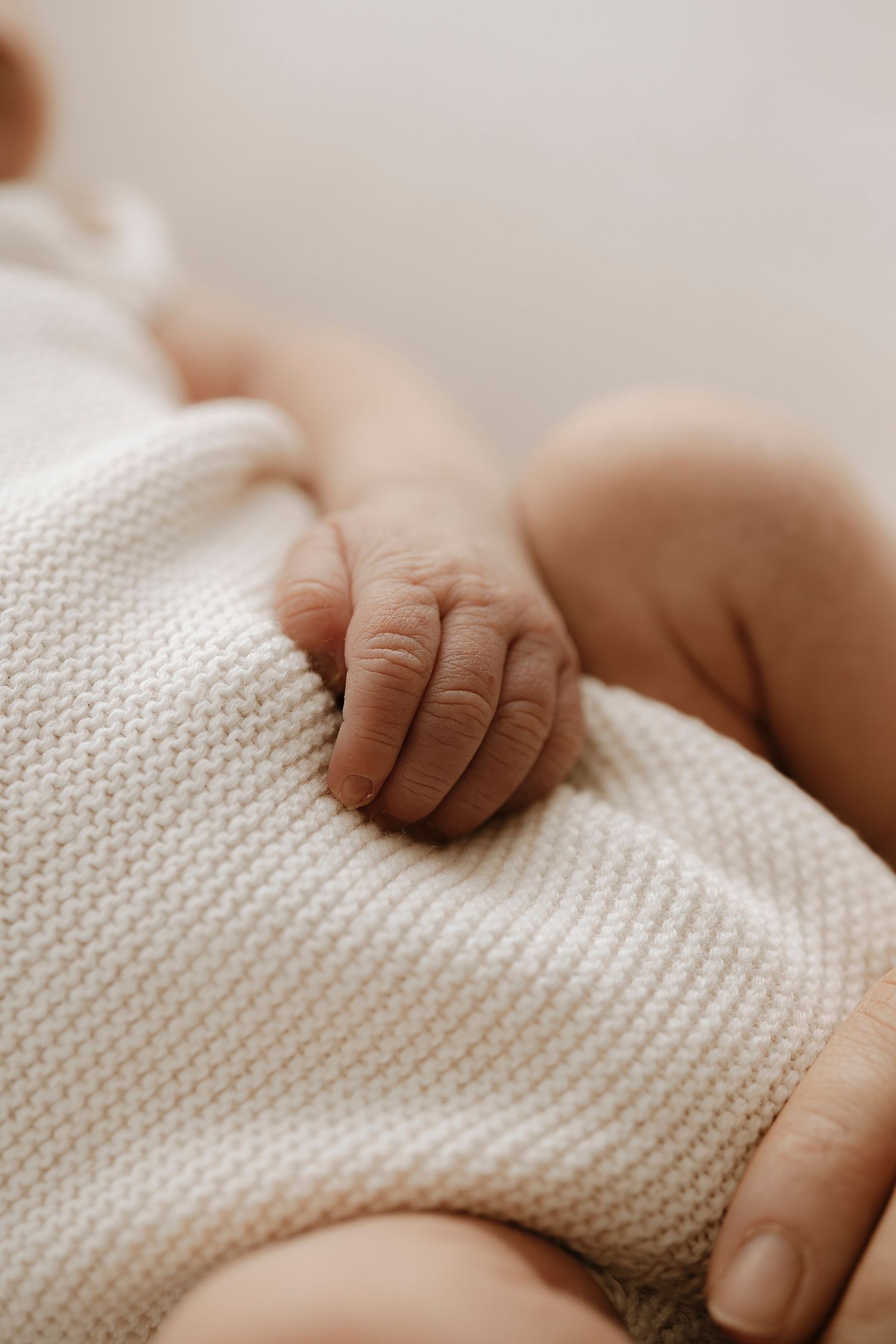 Peaceful newborn baby sleeping on soft beige cushion in natural light.