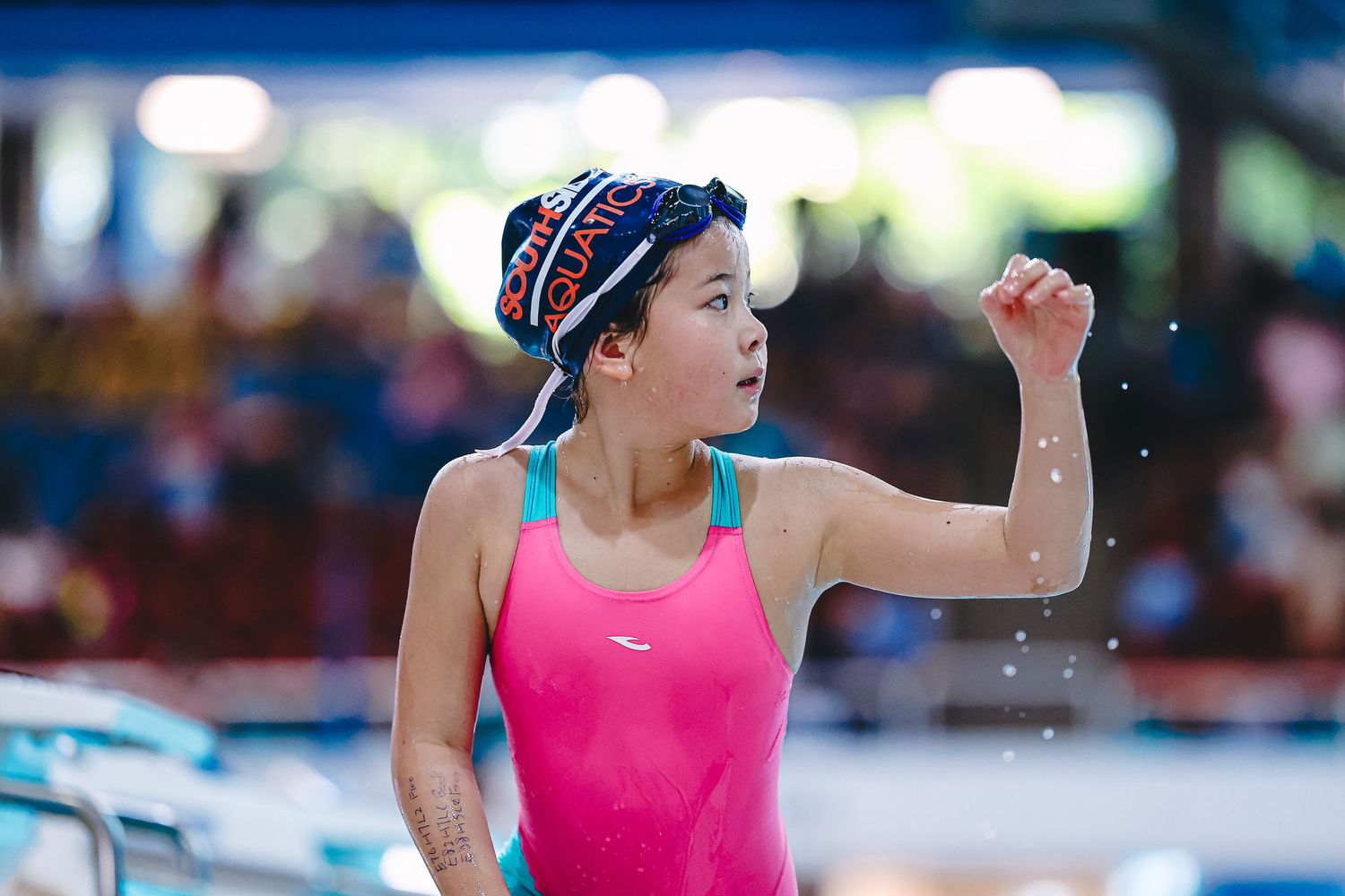 Competitive swimmer racing through blue pool water with orange lane dividers visible during competition.