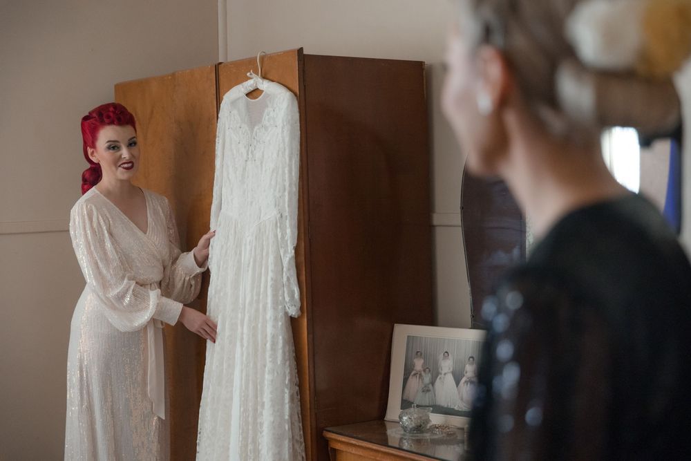 Wedding dress hanging from a vintage robe in a farmhouse bedroom on the morning of a private property wedding must have shot on a wedding