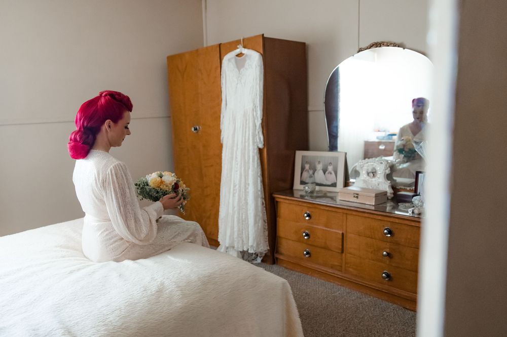 A moment of reflection bride spends time admiring her grandmother's wedding dress for her vintage inspired wedding in the country rural NSW