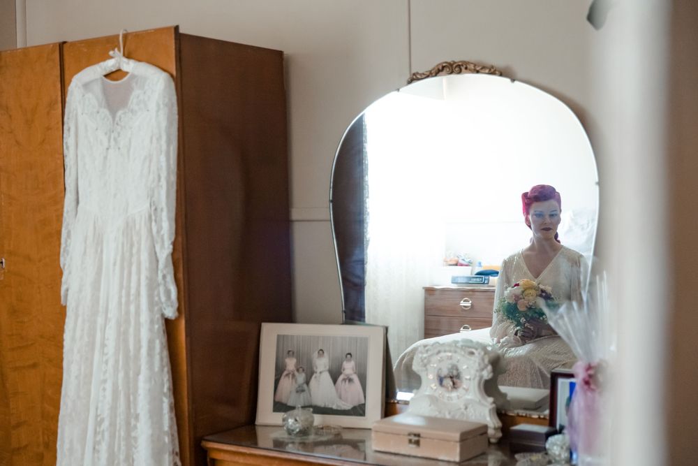 Wedding dress hanging from a vintage robe in a farmhouse bedroom on the morning of a private property wedding
