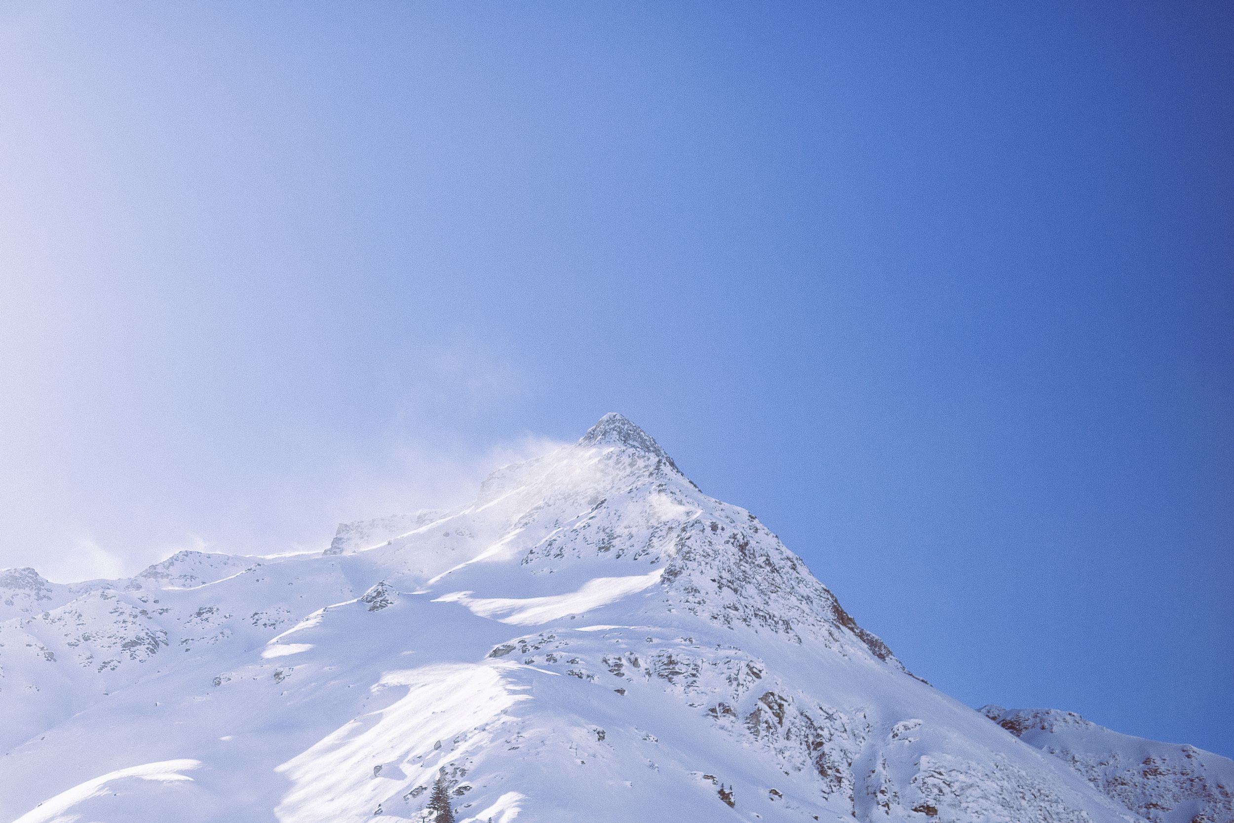 Panoramic view of snow-covered mountain peaks against a bright blue sky on a clear winter day.