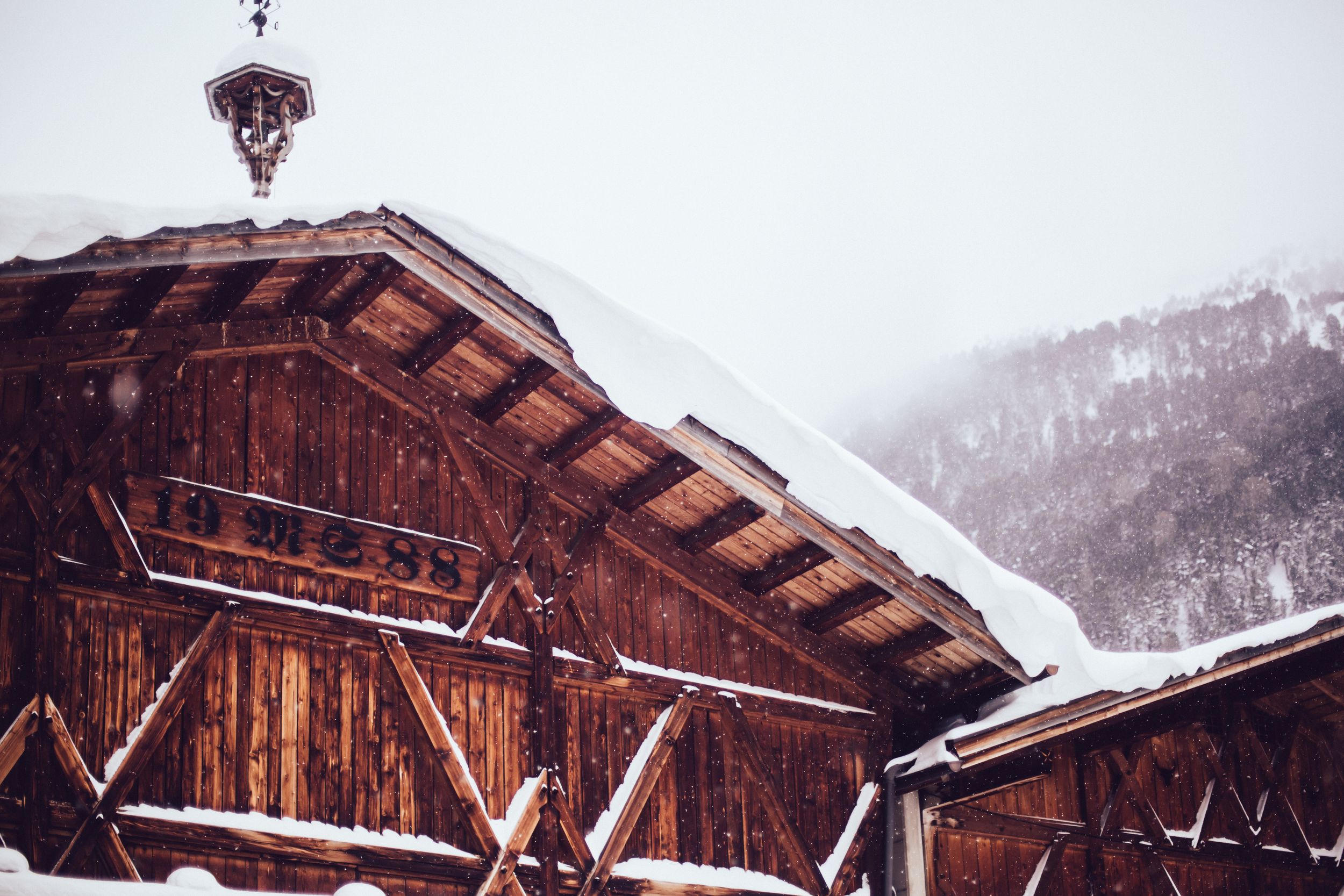 Snow-covered wooden chalets nestled in a mountainous winter landscape with overcast skies.