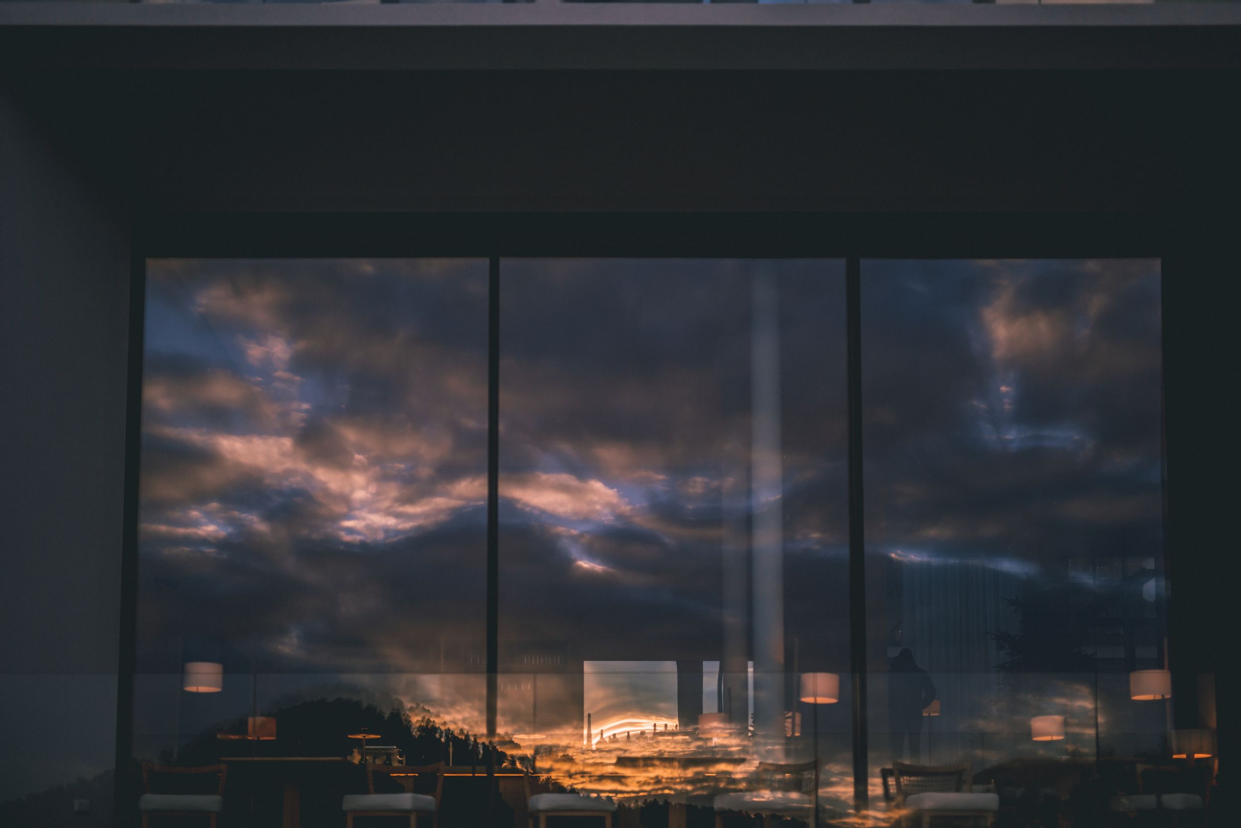 Dramatic sunset sky with pink and orange clouds reflecting over a dark industrial cityscape with power plant towers.