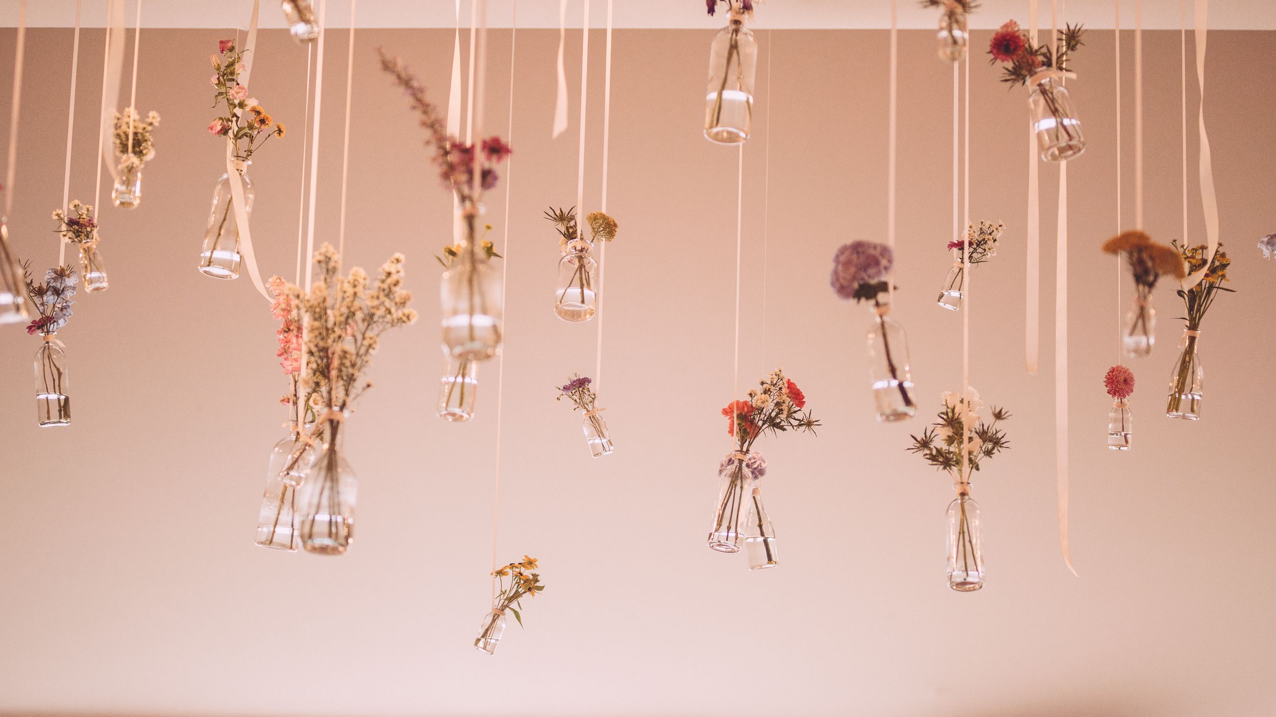 Delicate dried flowers and glass vials hang from strings creating an ethereal ceiling installation.