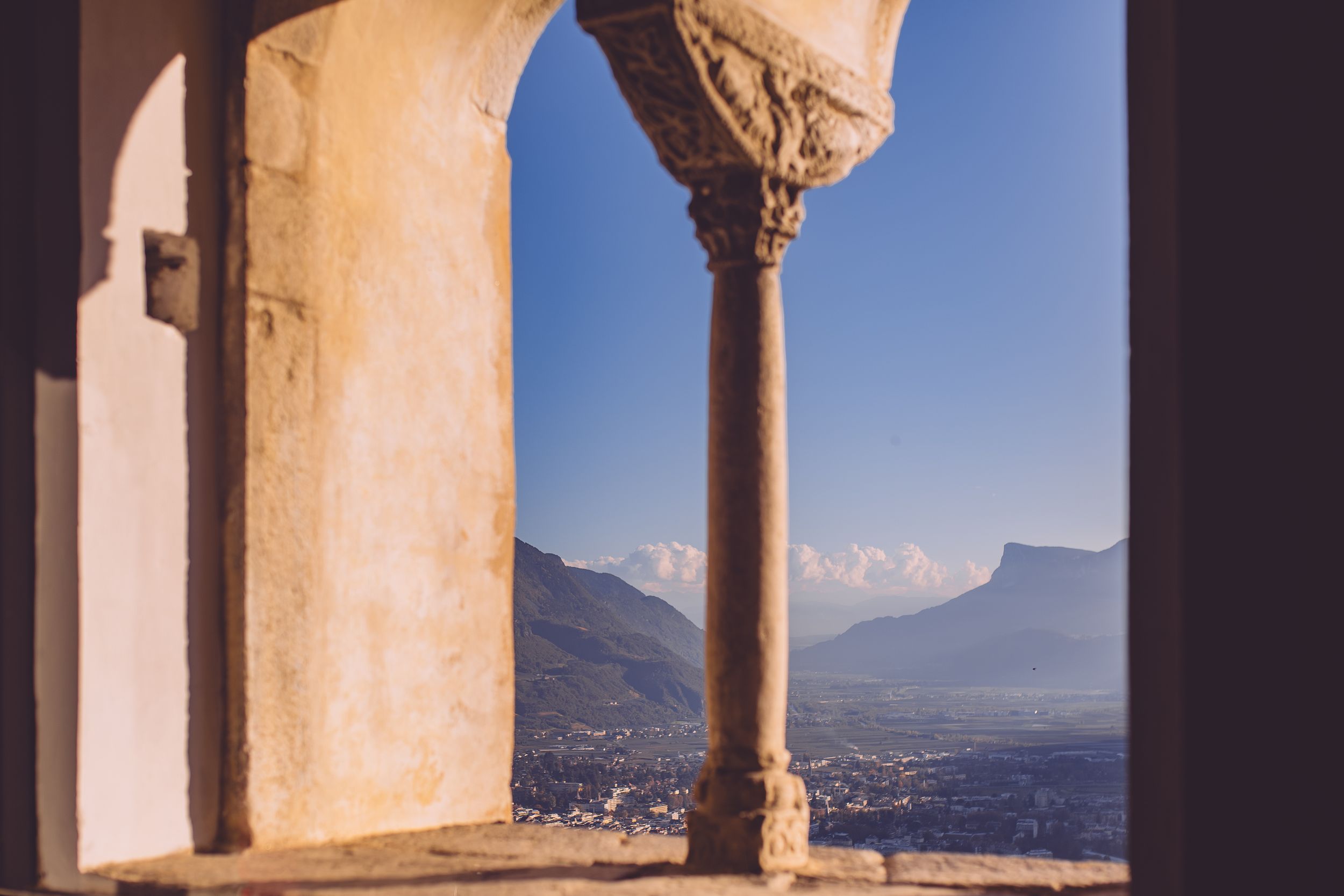 Scenic mountain view through stone archways of an ancient Mediterranean villa overlooking coastal waters.