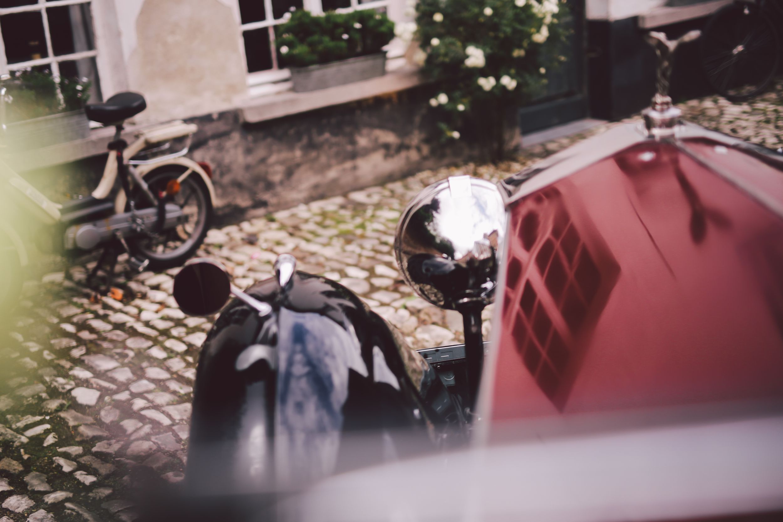 A row of vintage motorcycles parked on cobblestone streets with buildings in the background.