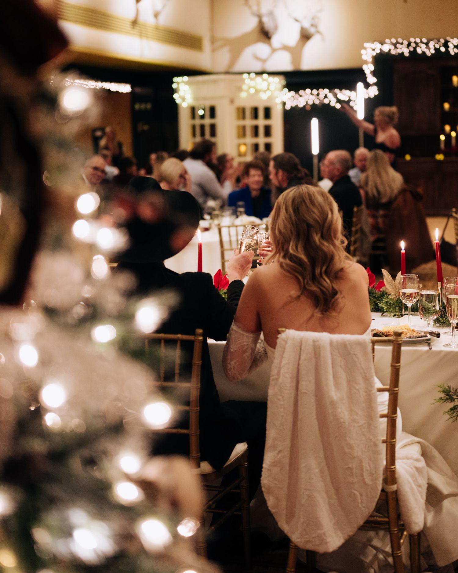 String lights illuminate a romantic evening wedding reception with glowing bokeh effects and silhouetted guests.