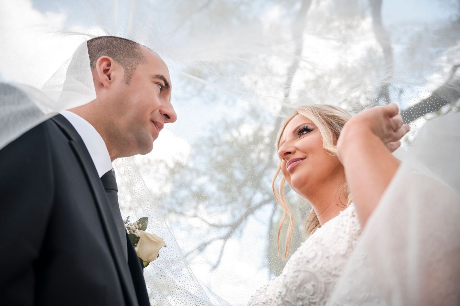A couple shares a romantic moment during their wedding ceremony under a cloudy sky.