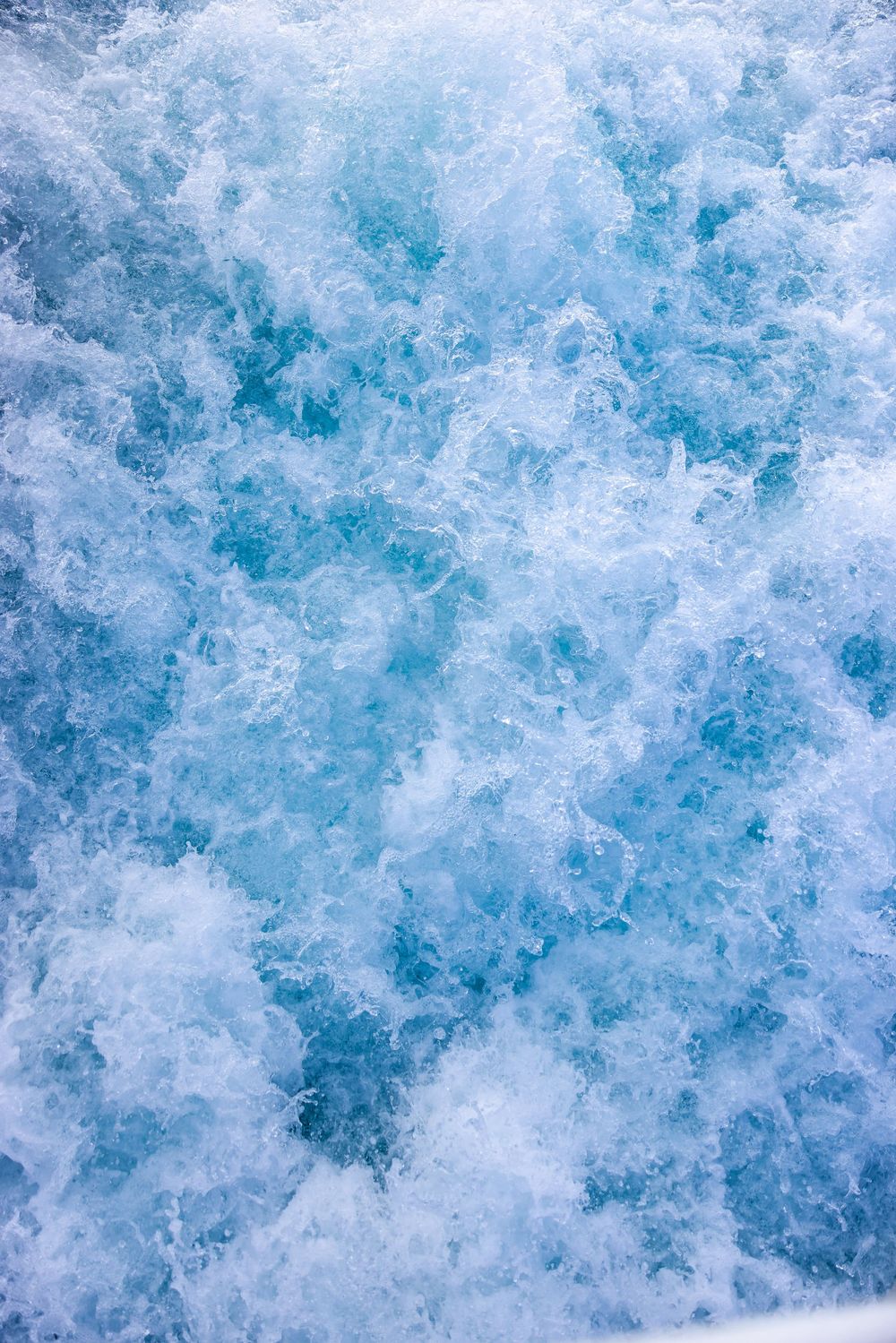 Abstract background texture of swirling blue and white water creating a dynamic frozen ice pattern.