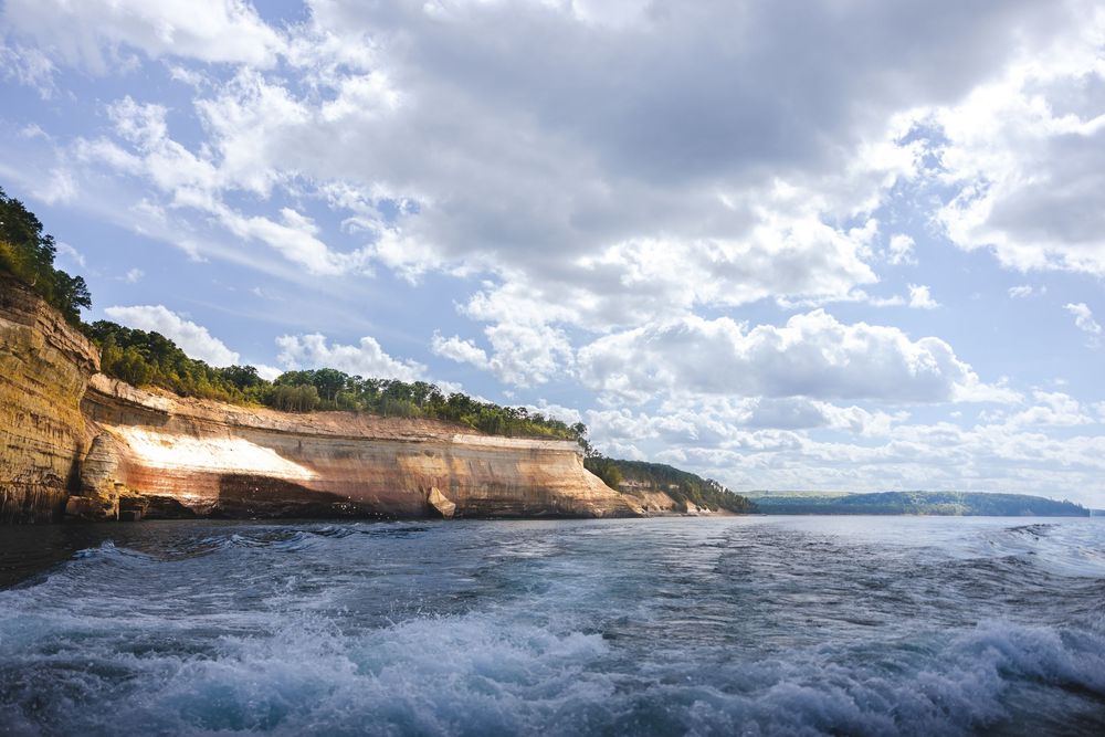 A series of coastal landscape photos showing dramatic ocean waves crashing against cliffs under cloudy skies.