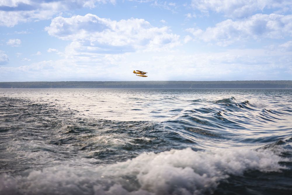 A helicopter flies over a vast ocean with rolling waves and cloudy skies in the background.